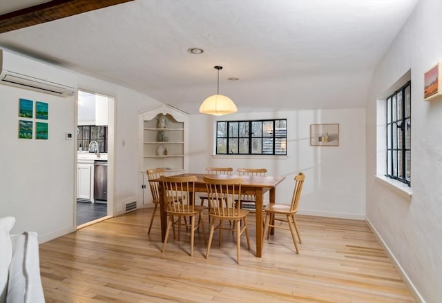 dining room featuring light hardwood / wood-style flooring, a wall mounted air conditioner, and built in features