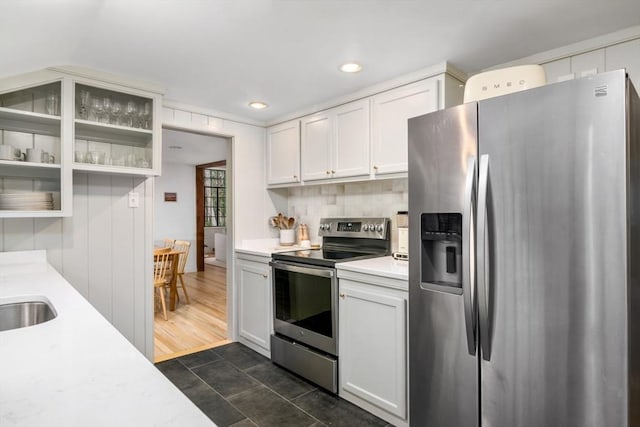 kitchen with sink, white cabinetry, dark tile patterned flooring, backsplash, and appliances with stainless steel finishes