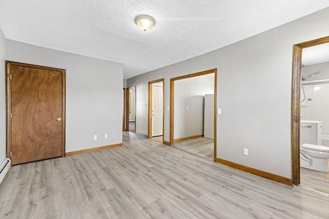 unfurnished bedroom featuring ensuite bath, baseboard heating, a textured ceiling, and light hardwood / wood-style floors