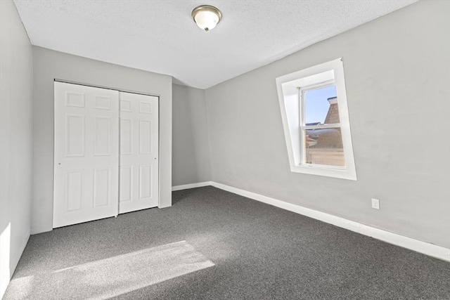 unfurnished bedroom featuring a textured ceiling, a closet, and dark colored carpet