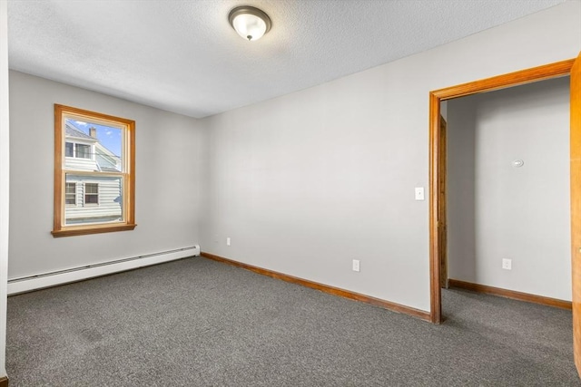 empty room featuring baseboard heating and dark colored carpet