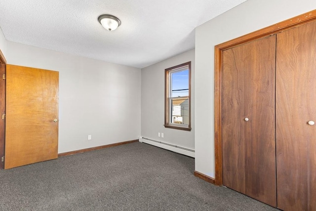 unfurnished bedroom with a baseboard heating unit, a closet, and dark colored carpet