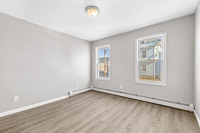 spare room with a baseboard heating unit and light hardwood / wood-style flooring