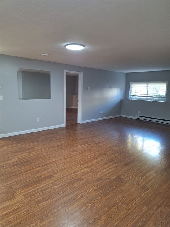 spare room with a baseboard radiator and dark hardwood / wood-style floors