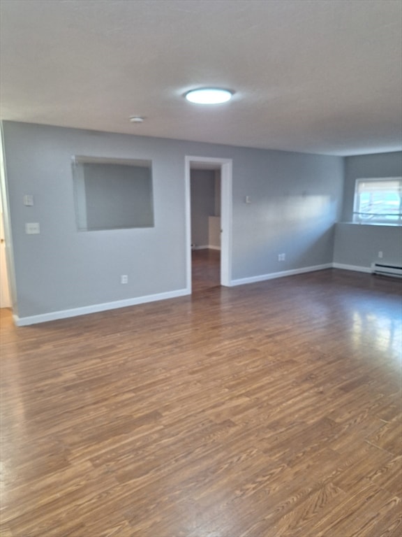 empty room with a baseboard radiator and dark hardwood / wood-style flooring