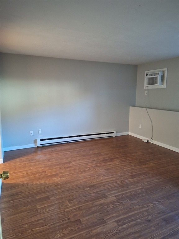 empty room with a wall mounted air conditioner, dark hardwood / wood-style floors, and baseboard heating