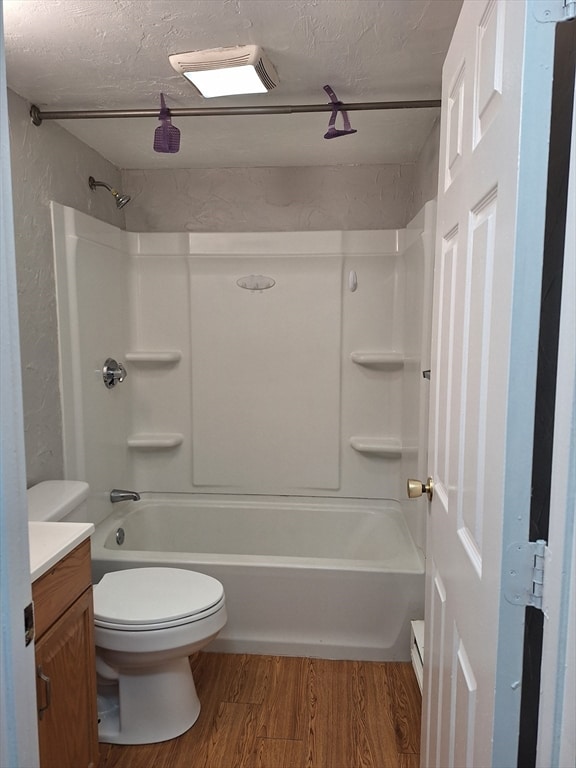 full bathroom with a textured ceiling, wood-type flooring, toilet, vanity, and washtub / shower combination