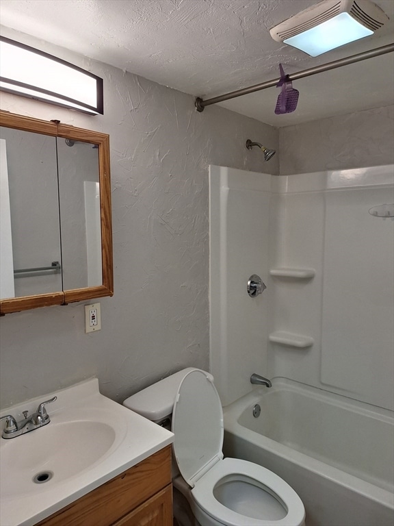 full bathroom featuring vanity, shower / bathing tub combination, a textured ceiling, and toilet