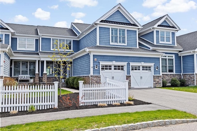 craftsman inspired home with fence, a standing seam roof, stone siding, and concrete driveway
