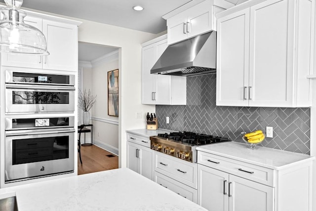 kitchen with under cabinet range hood, backsplash, baseboards, and appliances with stainless steel finishes