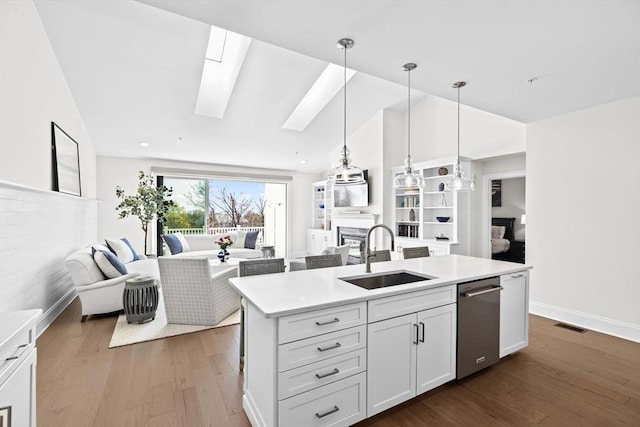 kitchen with open floor plan, a glass covered fireplace, a sink, and lofted ceiling with skylight