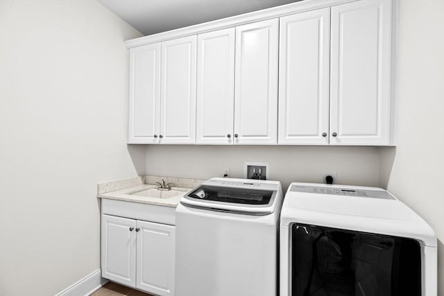 clothes washing area featuring cabinet space, separate washer and dryer, baseboards, and a sink