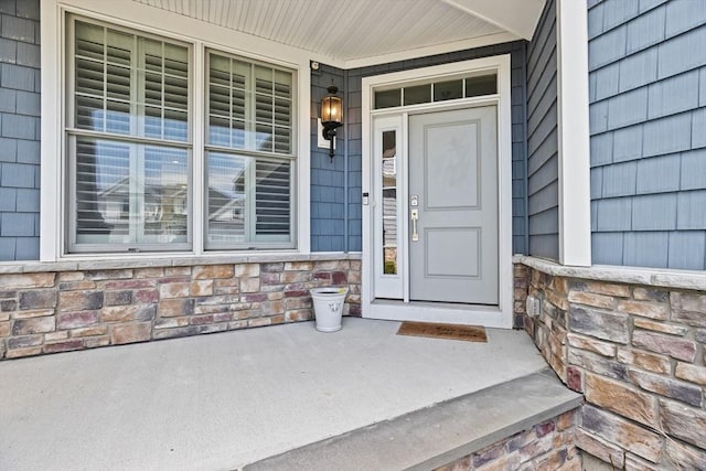 doorway to property with covered porch and stone siding