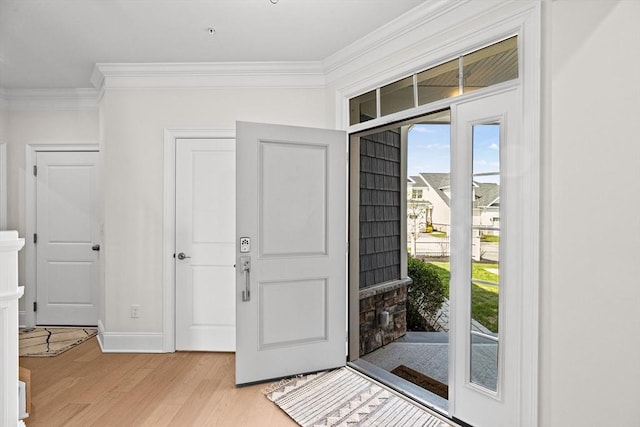 foyer with light wood-style floors and ornamental molding