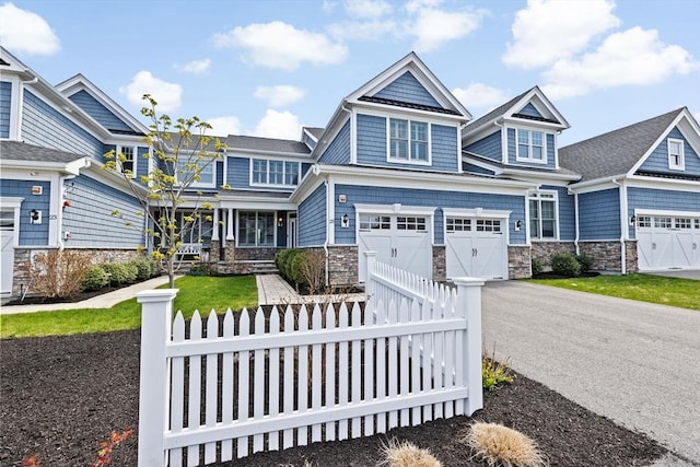 craftsman house featuring an attached garage, fence, driveway, and stone siding