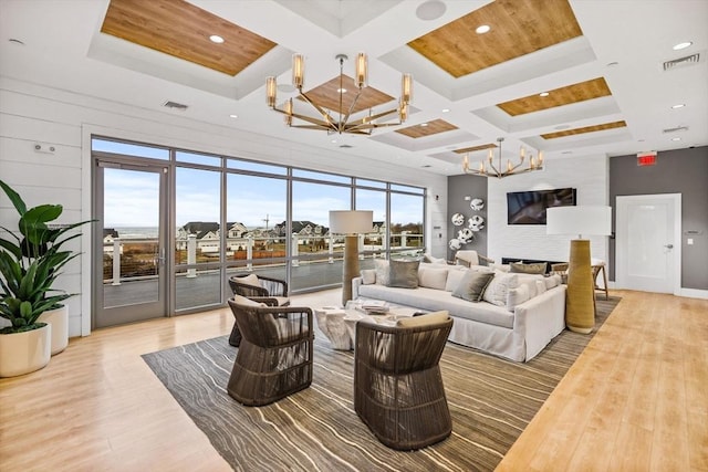 living area with visible vents, beamed ceiling, a chandelier, coffered ceiling, and light wood finished floors