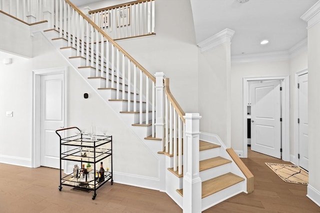 stairs featuring recessed lighting, baseboards, ornamental molding, and wood finished floors