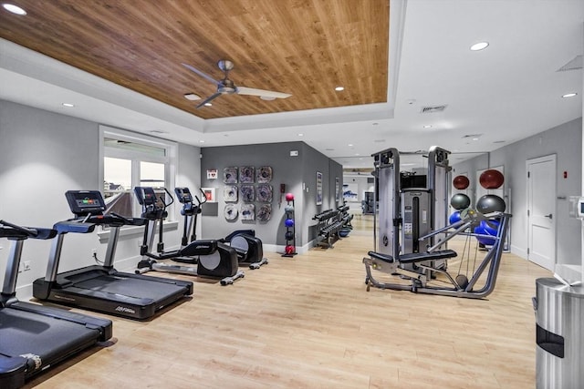 gym with a ceiling fan, visible vents, wood finished floors, a raised ceiling, and recessed lighting
