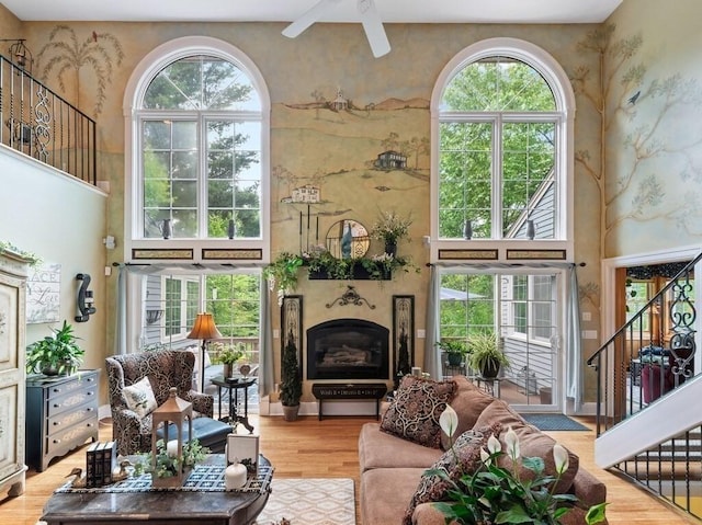 101 Colonial Dr Unit 101, Sturbridge, MA 01566 - living room featuring stairway, a high ceiling, a glass covered fireplace, ceiling fan, and wood finished floors