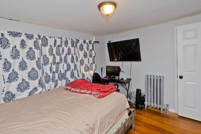 bedroom with radiator and hardwood / wood-style flooring