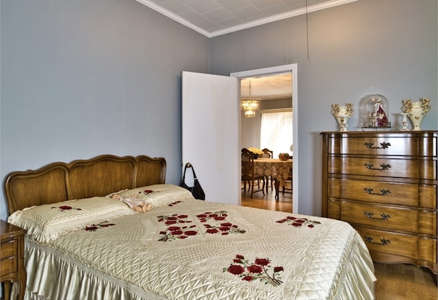 bedroom with crown molding, hardwood / wood-style flooring, and a chandelier