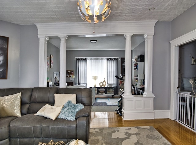 living room with a notable chandelier, ornate columns, hardwood / wood-style flooring, and ornamental molding