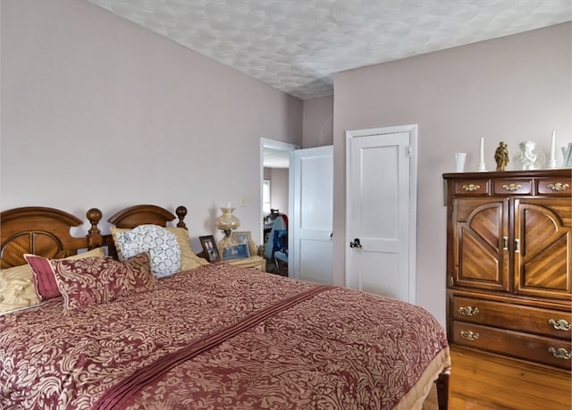 bedroom with a textured ceiling and light hardwood / wood-style flooring