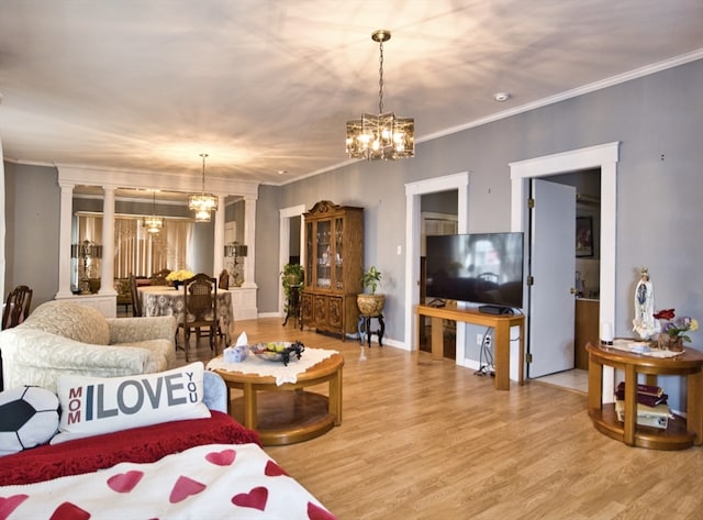 living room featuring decorative columns, wood-type flooring, an inviting chandelier, and ornamental molding