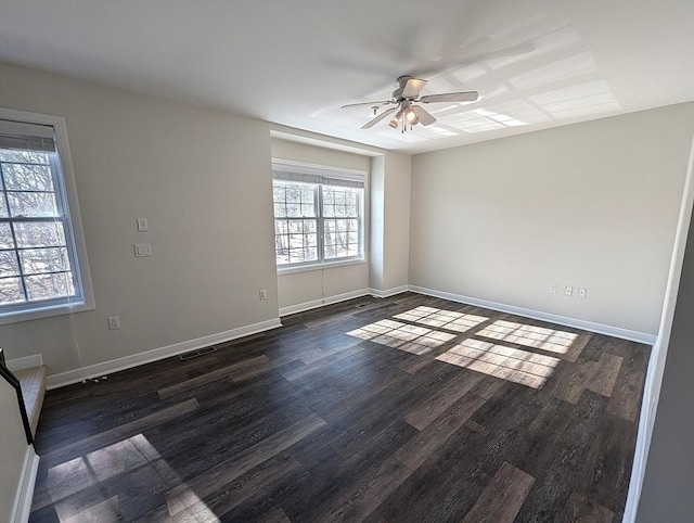 empty room featuring a ceiling fan, baseboards, visible vents, and dark wood-style flooring