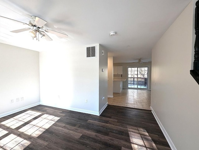 empty room with a ceiling fan, baseboards, visible vents, and wood finished floors