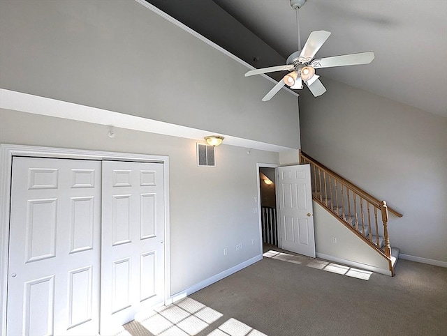 unfurnished living room featuring carpet floors, visible vents, high vaulted ceiling, baseboards, and stairs