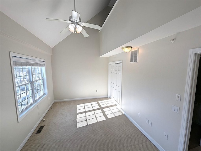 carpeted empty room with high vaulted ceiling, visible vents, and baseboards