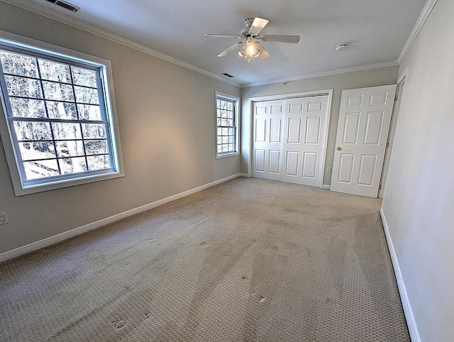 unfurnished bedroom with a closet, baseboards, crown molding, and light colored carpet