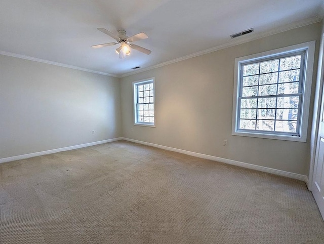 spare room featuring ceiling fan, light colored carpet, visible vents, baseboards, and crown molding