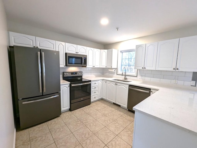 kitchen featuring appliances with stainless steel finishes, white cabinetry, a sink, and tasteful backsplash