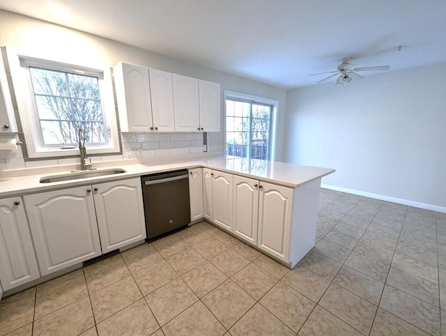 kitchen with a peninsula, a sink, light countertops, backsplash, and dishwasher