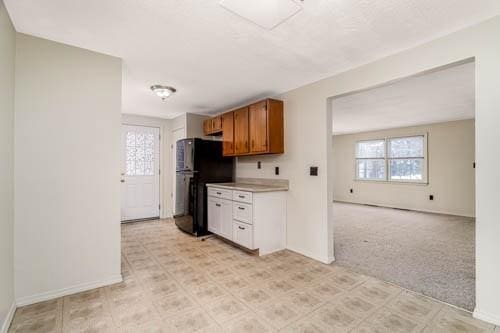 kitchen with black refrigerator and light carpet