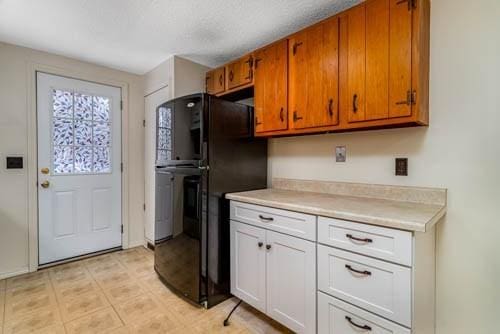 kitchen with white cabinetry and black fridge