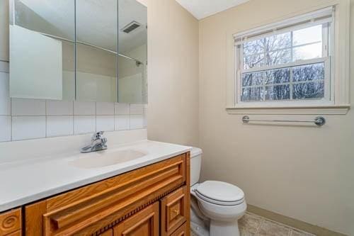 bathroom featuring tasteful backsplash, vanity, toilet, and tile patterned flooring