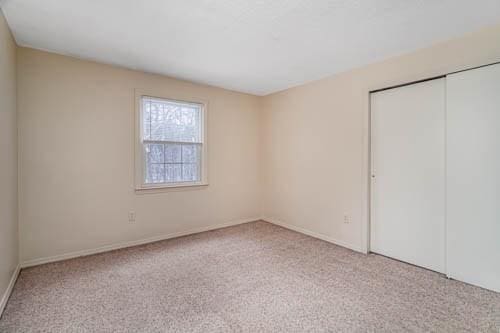 unfurnished bedroom with light carpet and a closet