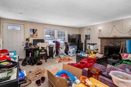 living room featuring a brick fireplace and carpet floors