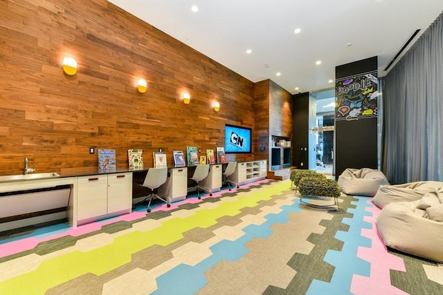 playroom featuring built in desk, light colored carpet, and wooden walls