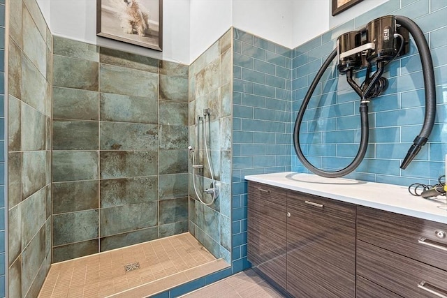 bathroom featuring tiled shower, vanity, and tile walls