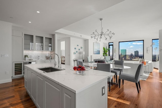 kitchen with white cabinetry, an island with sink, sink, and light stone counters