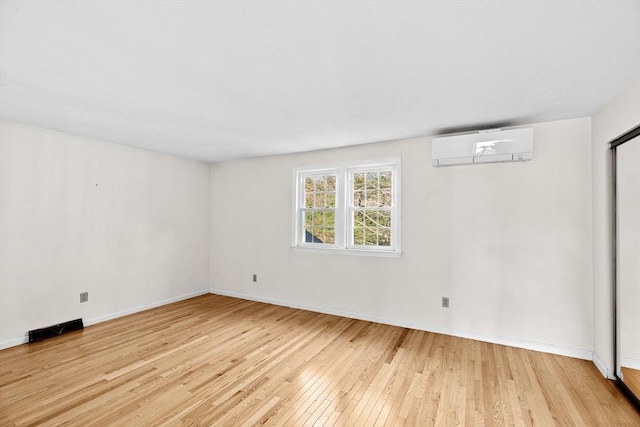 unfurnished room featuring light hardwood / wood-style floors and a wall mounted AC