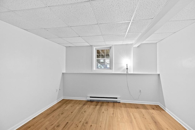 basement featuring baseboard heating and light hardwood / wood-style flooring