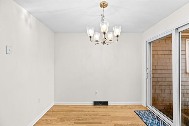 unfurnished dining area with a chandelier and hardwood / wood-style floors