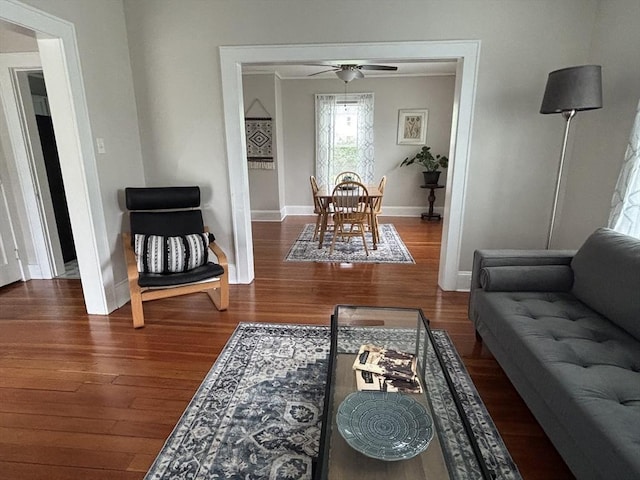 living room with a ceiling fan, baseboards, and wood finished floors