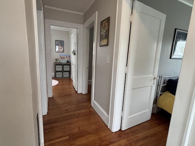 hallway featuring baseboards, ornamental molding, and dark wood finished floors