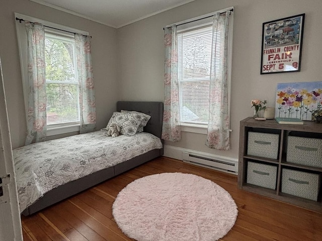 bedroom with ornamental molding, baseboards, baseboard heating, and wood finished floors